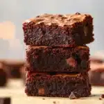Fudgy gluten-free brownies served on a plate, topped with a scoop of vanilla ice cream.
