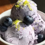 Delicious homemade blueberry ice cream served in a bowl with fresh blueberries.