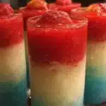 Colorful layered tequila slushie with fruity flavors and garnish.