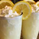 A refreshing glass of whipped lemonade topped with cream and lemon slices.